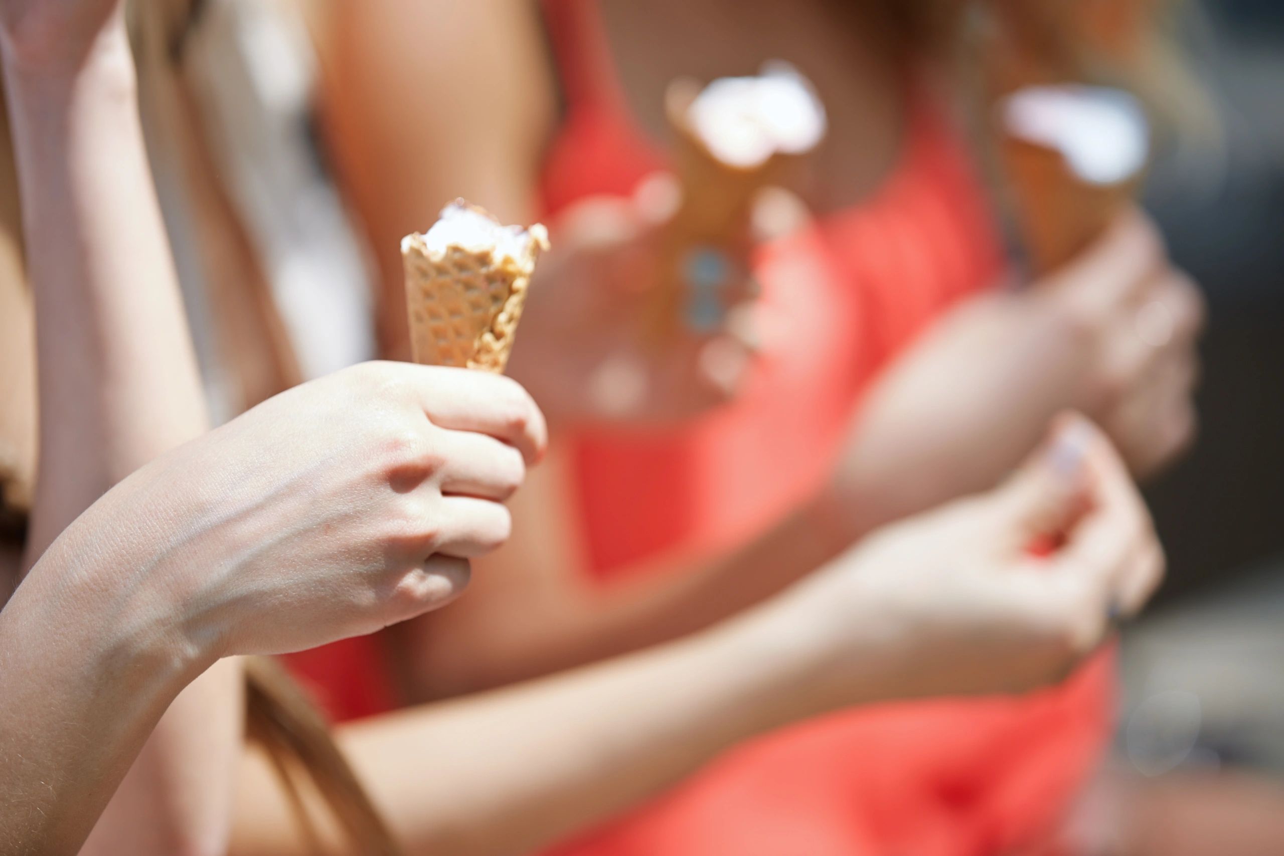 Hands holding ice cream cones at an outdoor celebration