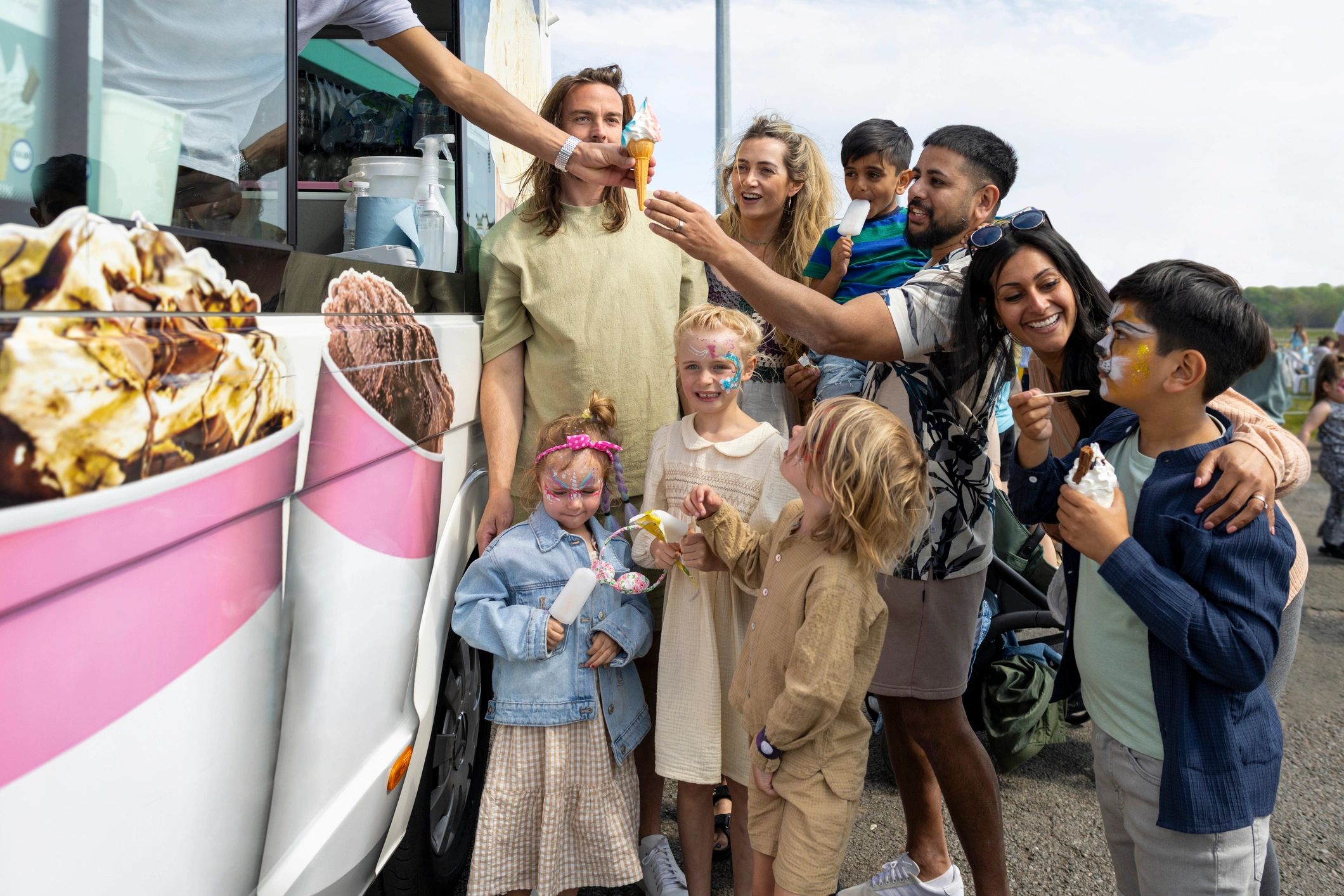 Families ordering ice cream from a vintage-style ice cream van at an outdoor fair