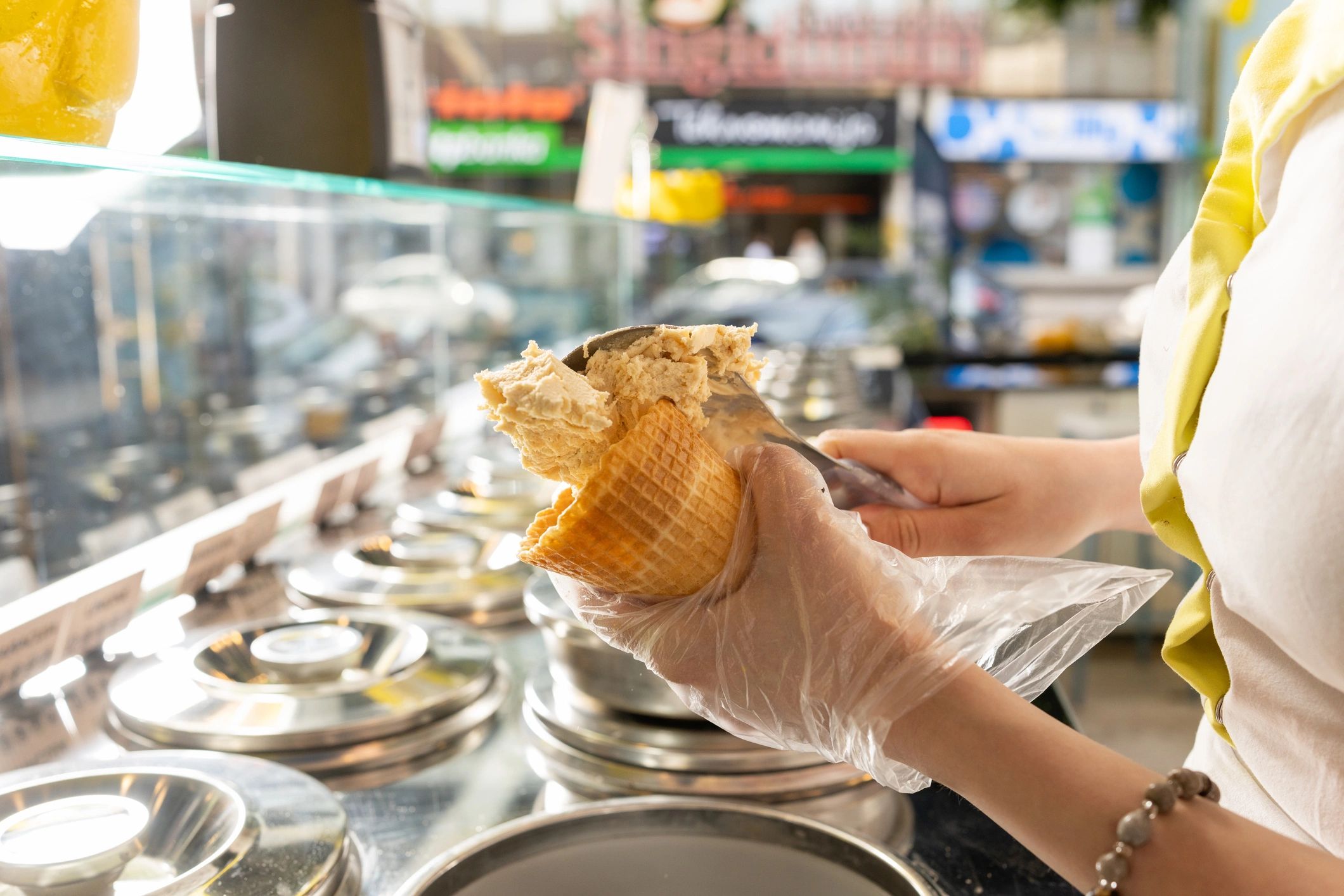 Ice cream server scooping a cone in a bright ice cream shop